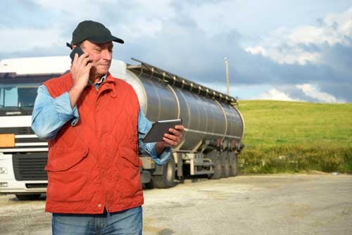 Truck driver on phone while reviewing fleet management device